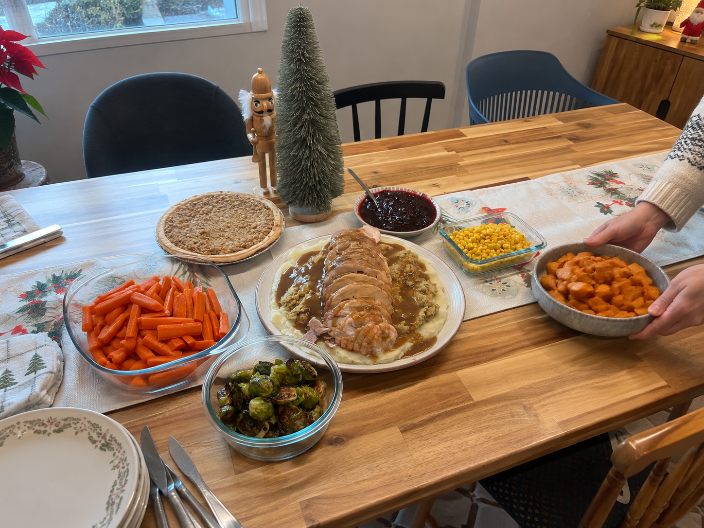 A hand setting a bowl onto a set holiday dinner table